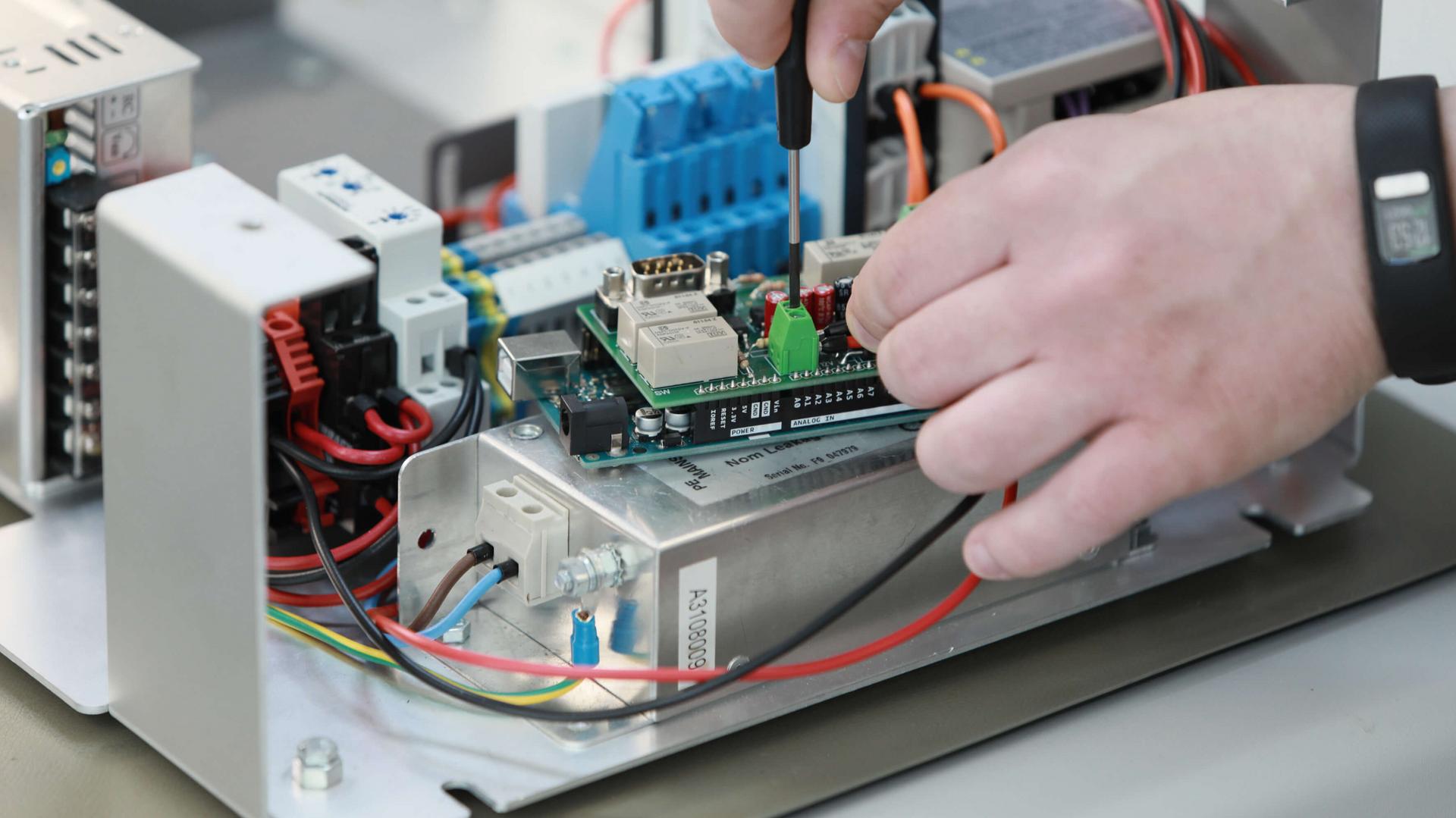 Person führt eine Strommessung an einer Platine durch